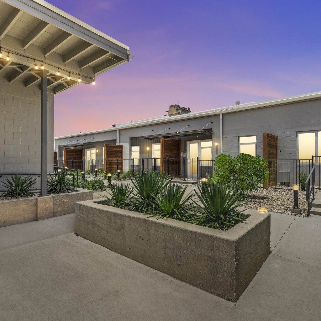 Exterior landscaping and well-lit entry area at the Hawn West apartment homes at dusk.