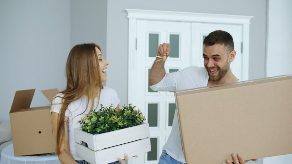 Happy couple carrying moving boxes and house keys into their new home